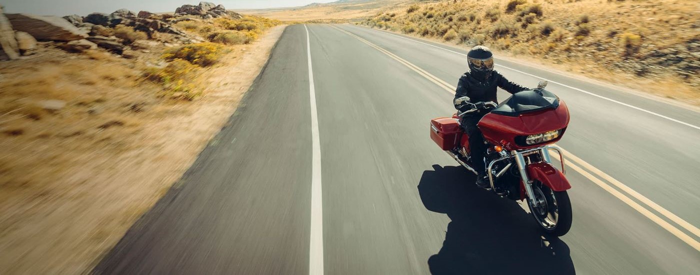 A red 2022 Harley-Davidson Road Glide is shown driving on an open road.