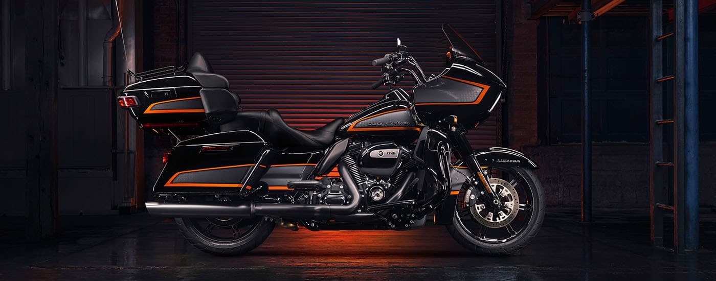 A black and orange 2022 Harley-Davidson Road Glide Limited is shown from the side parked in a …