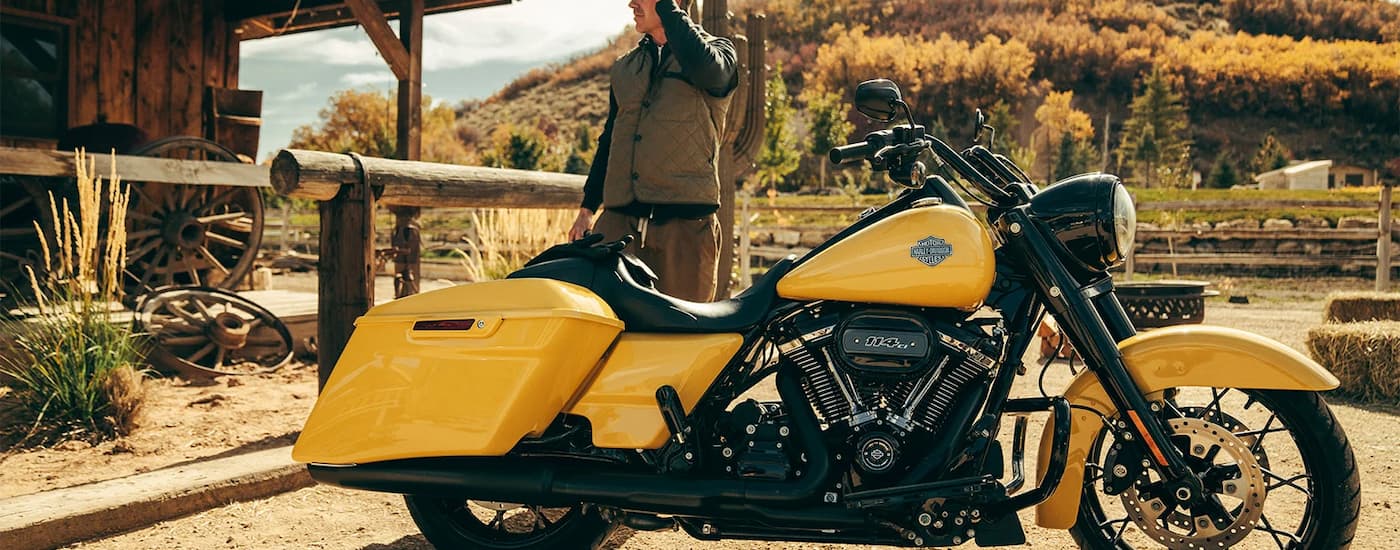A yellow 2022 Harley-Davidson Road King Special is shown from the side parked near a ranch.