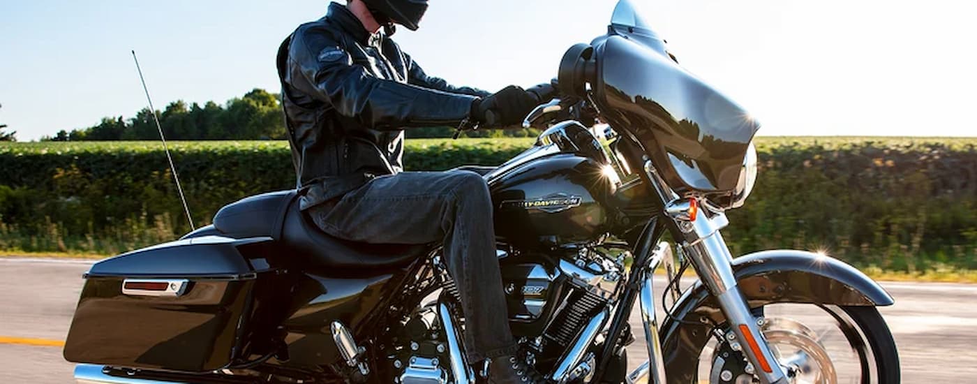 A black 2022 Harley-Davidson Street Glide is shown from the side driving past a corn field.