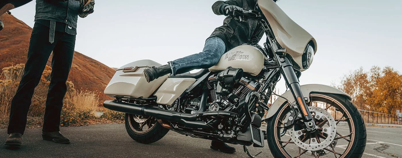 A person is shown getting onto a white 2023 Street Glide ST.