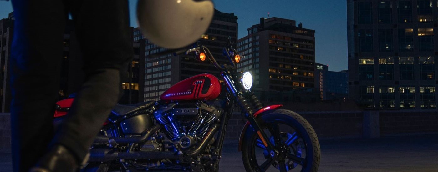 A person is shown approaching a red 2021 Harley-Davidson Street Bob 114 at night,