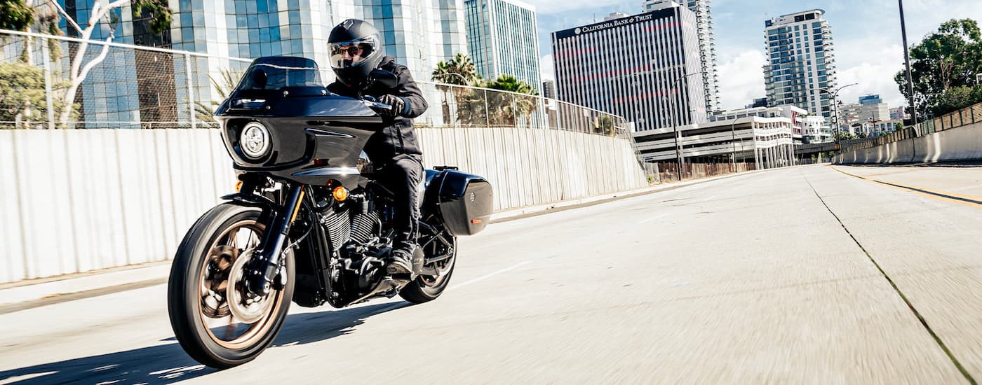 A black 2022 Harley-Davidson Low Rider ST is shown driving on a city street after looking at a …