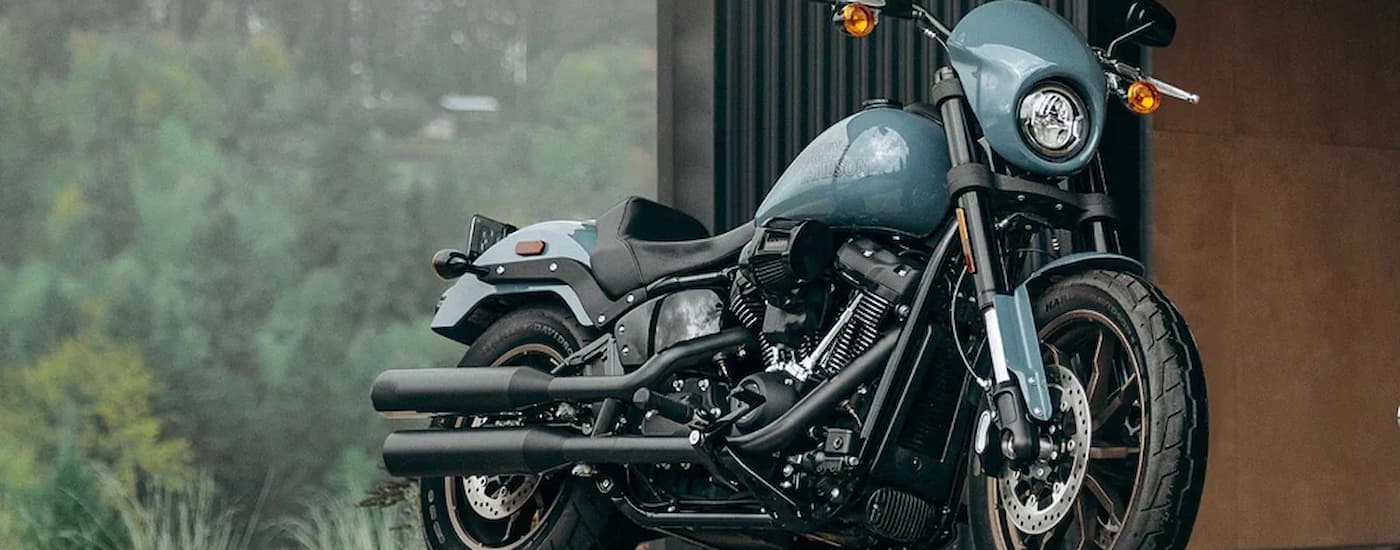 A blue 2024 Harley-Davidson Low Rider S parked next to a building.