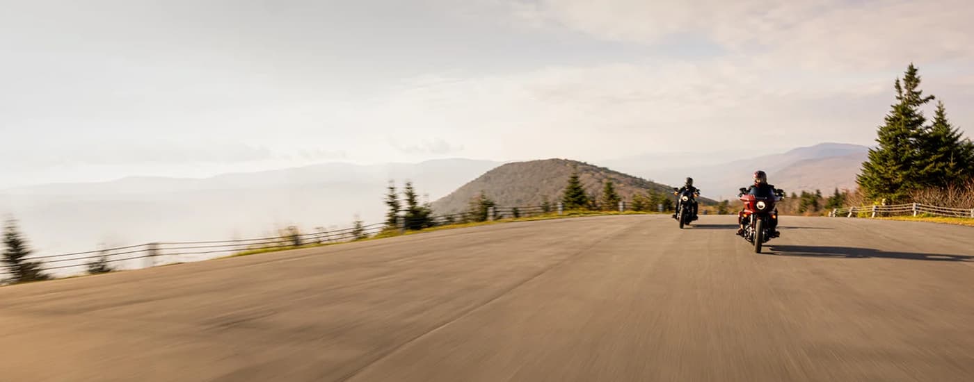 A grey and an orange 2024 Harley-Davidson Low Rider for sale driving on an open road.