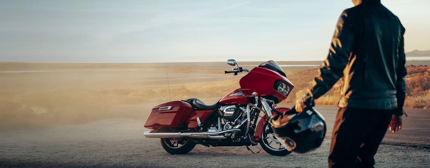 A man is shown walking towards a red 2023 Harley-Davidson Road Glide parked in a desert.