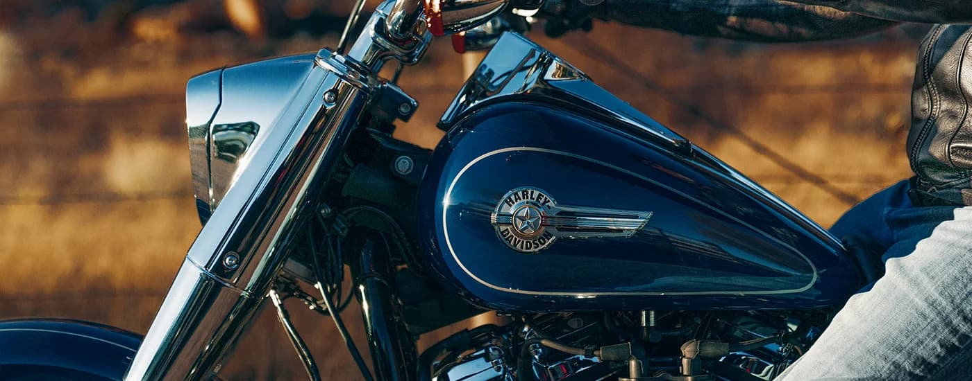 A close up of the front side of a blue 2023 Harley-Davidson Fat Boy 114 is shown.