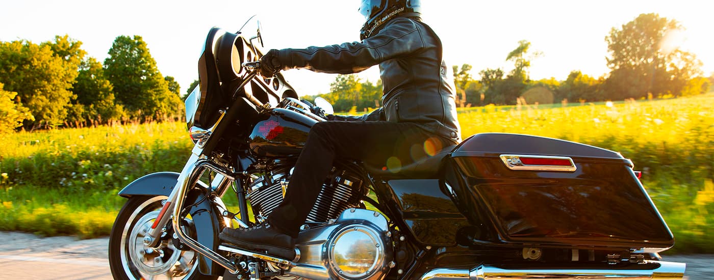 A person is shown riding a 2022 Harley-Davidson Electra Glide is shown driving next to a field.