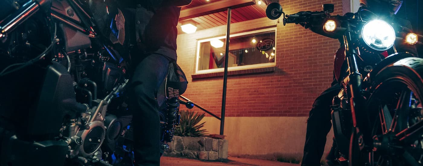 Two 2023 Harley-Davidson Nightster riders are shown at night near a brick building.