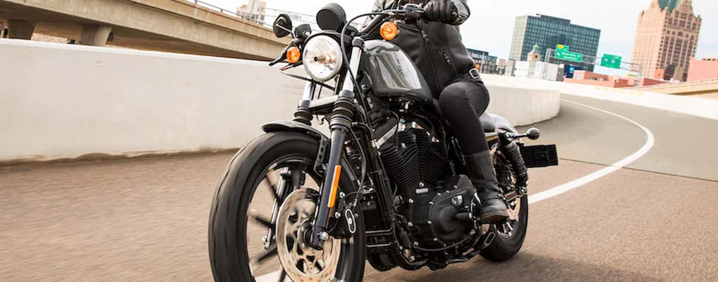 A black 2022 Harley-Davidson Iron 883 is shown driving on a highway after leaving a used …